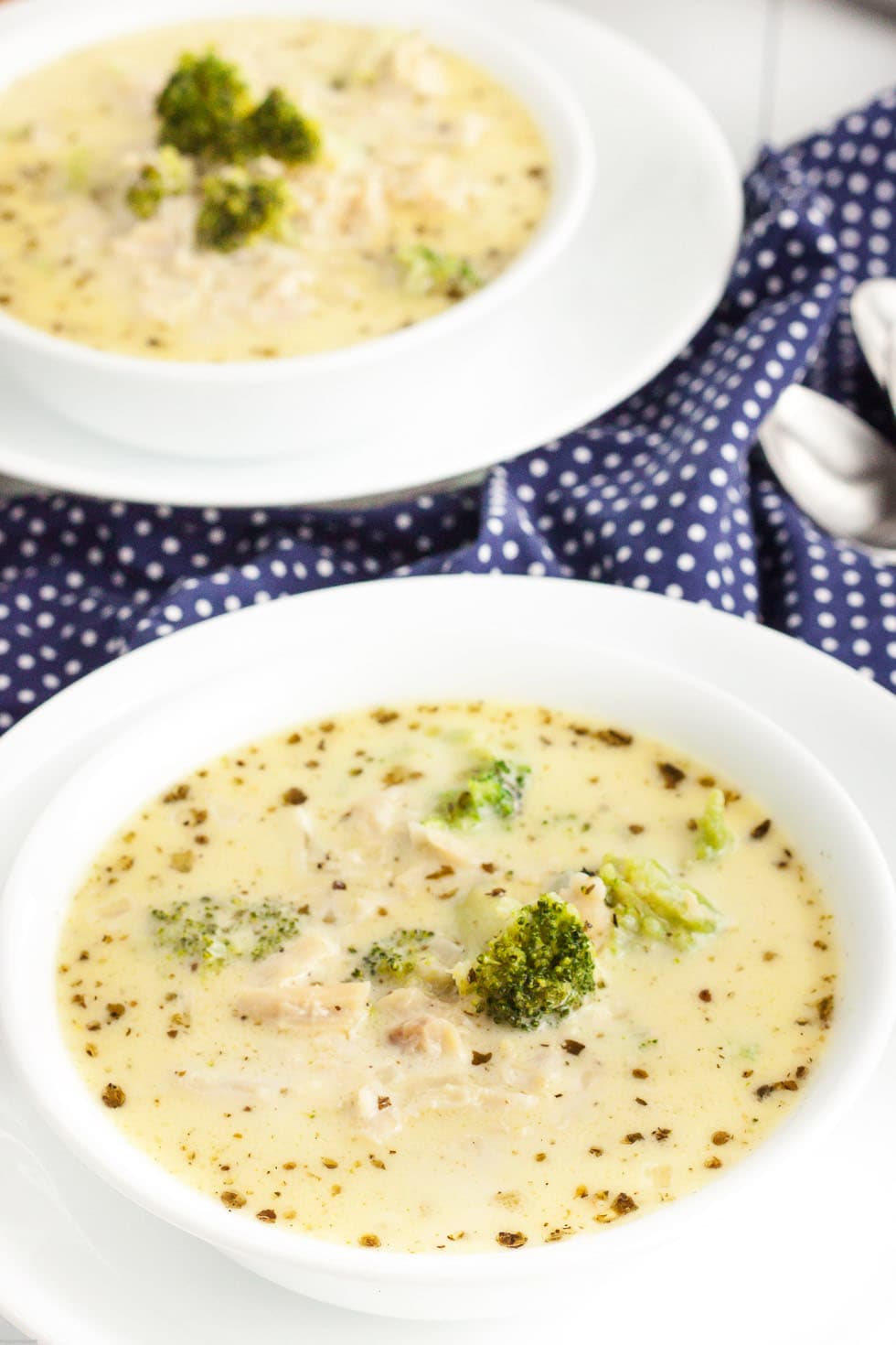 two bowls of keto chicken alfredo soup next to a blue and white polkadot background