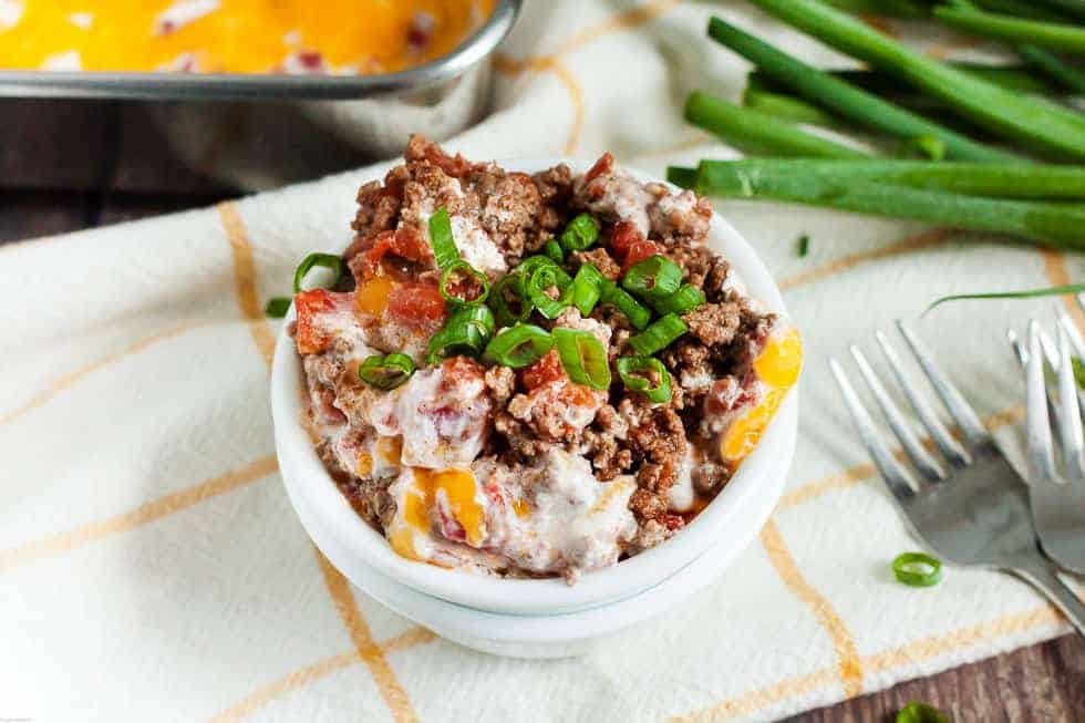 closeup of keto ground beef casserole in a white bowl next to a casserole dish