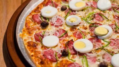 half of a keto pizza on a silver platter with hard boiled egg on top