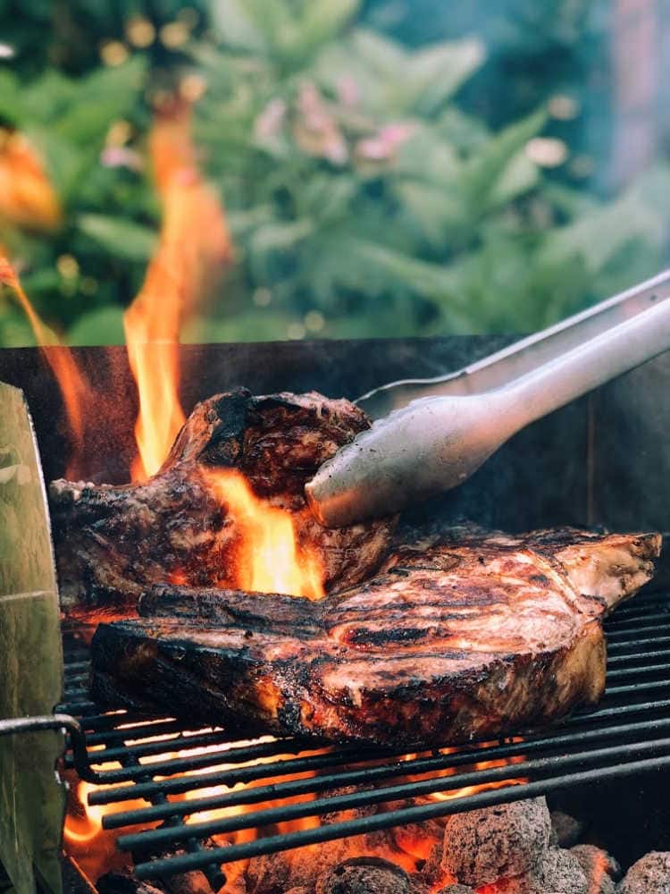 two steaks being grilled over an open flame to consume on the carnivore diet