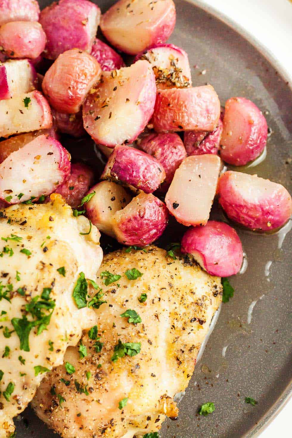 overhead view of sheet pan chicken thighs cooked next to seasoned roasted radishes