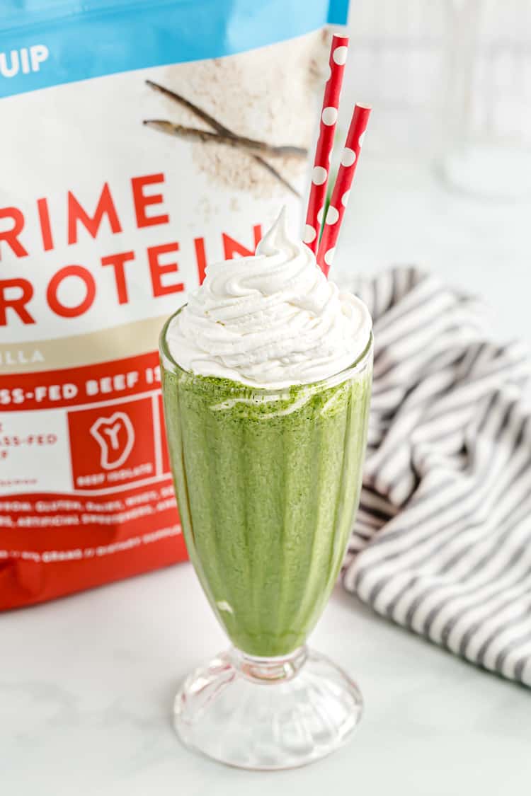 a keto shamrock shake with whipped cream on top and red and white straws