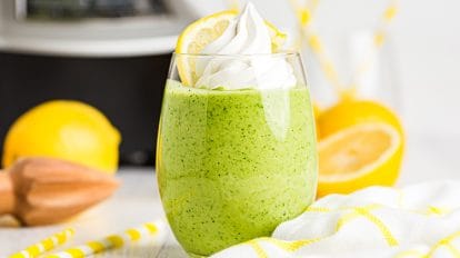 keto lemon smoothie topped with whipped cream in front of a blender