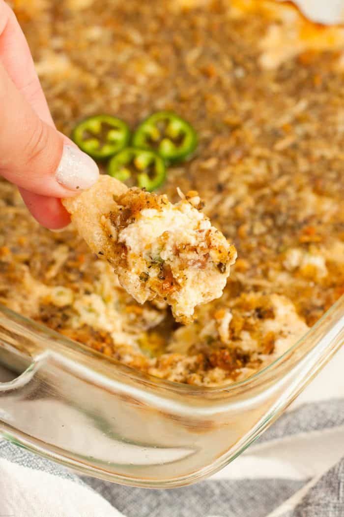 hand in keto dip recipe holding a pork rind