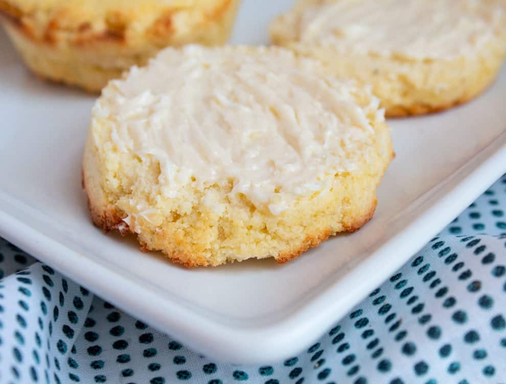 closeup of keto cornbread muffins on a white plate cut in half with butter