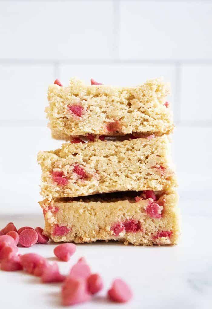 three keto strawberry cookies stacked next to keto strawberry chips