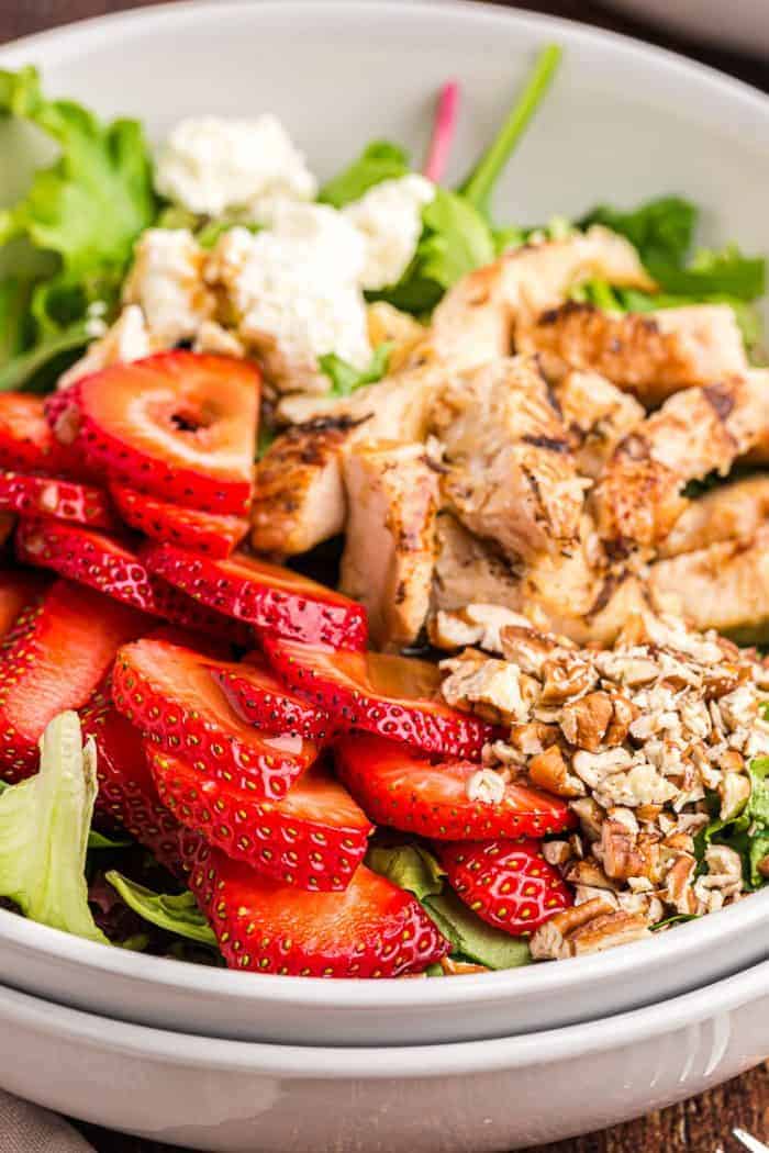 large bowl of keto strawberry salad with pieces of chicken and feta cheese