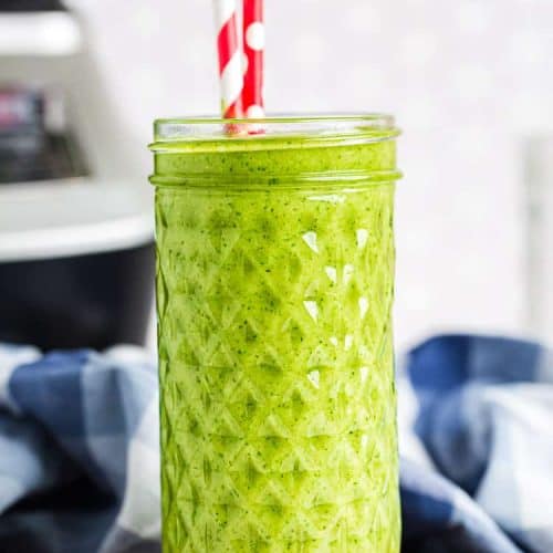 Vanilla Ice Cream Keto Green Smoothie in a tall glass with two red and white straws