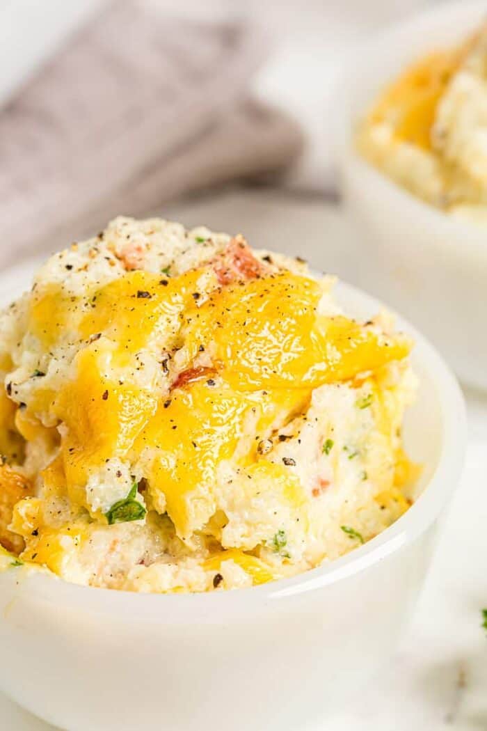 cheesy cauliflower casserole in a small dish with cheese on top