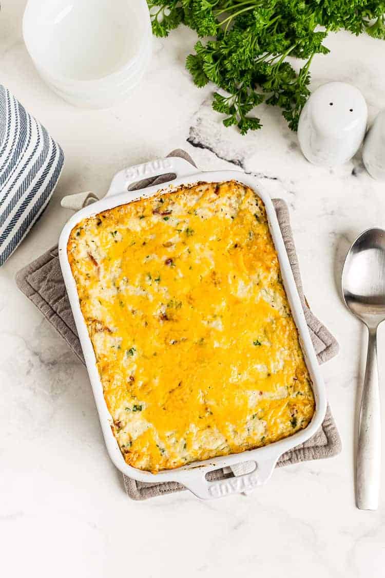 overhead view of fully baked cauliflower cheese casserole keto dish next to parsley