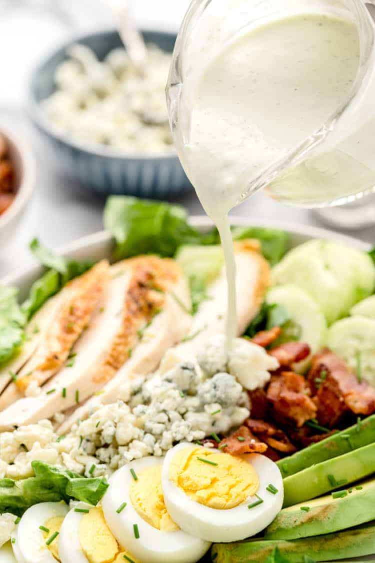 dressing being poured onto healthy cobb salad