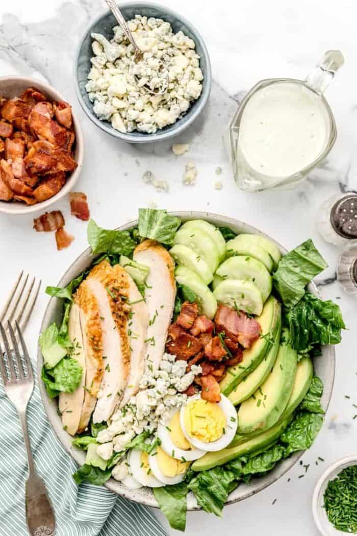 overhead view of keto cobb salad next to bowls of bacon, cheese, and dressing