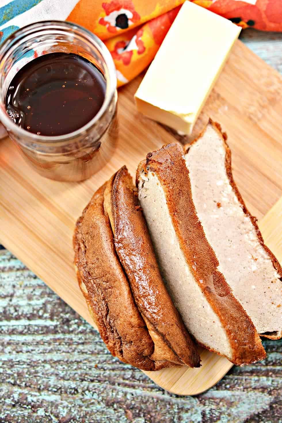 overhead view of sliced keto french toast eggloaf loaf on a wooden cutting board next to butter