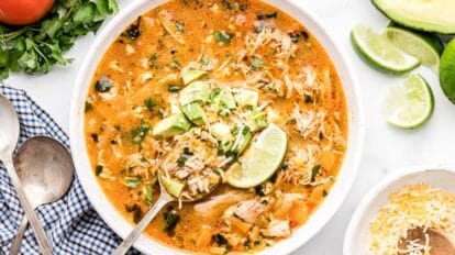 bowl of keto chicken enchilada soup with spoon holding up serving