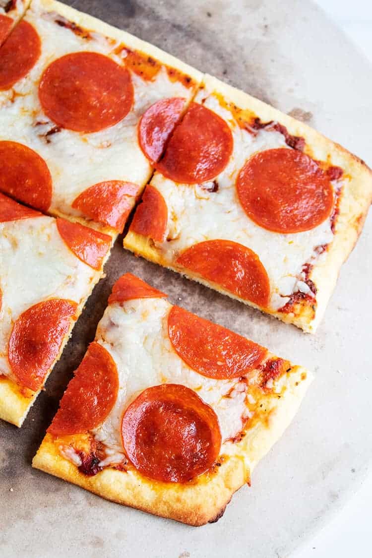 overhead view of slices of keto pepperoni pizza on pizza stone