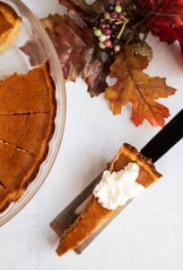 thin slice of keto pumpkin pie next to fall foliage