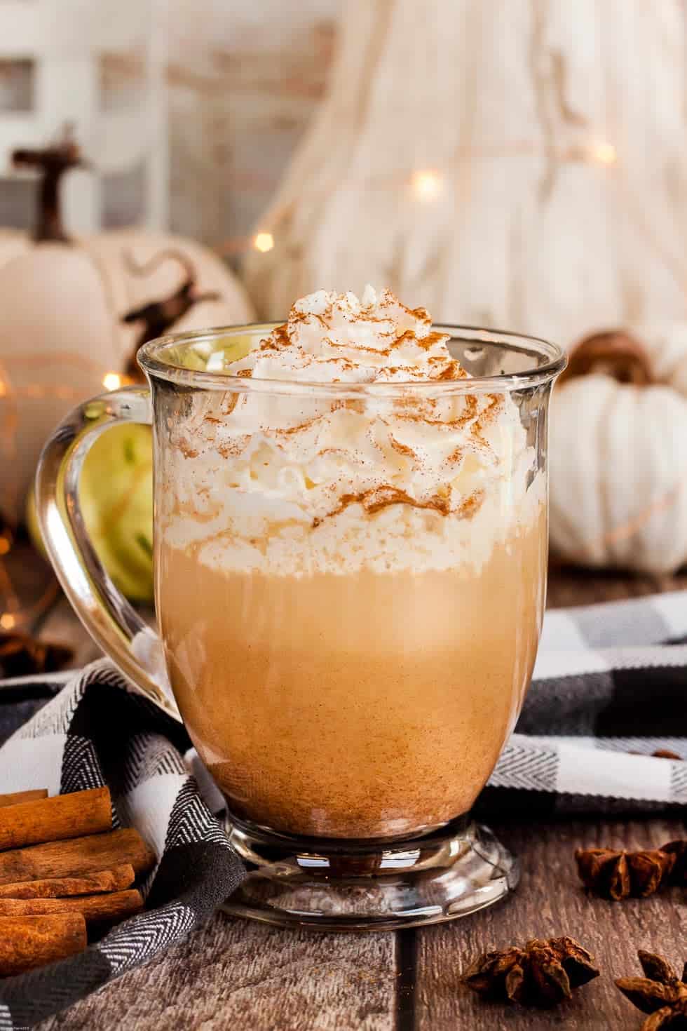keto pumpkin spice latte with keto whipped cream on top in front of a white and beige pumpkin