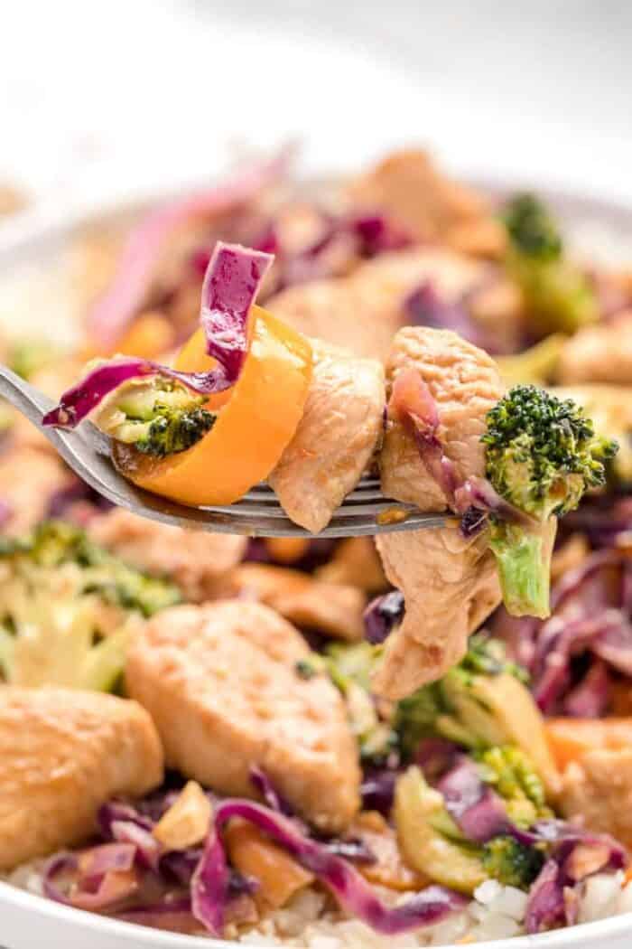 closeup view of keto stir fry with piece of chicken and vegetables on a fork