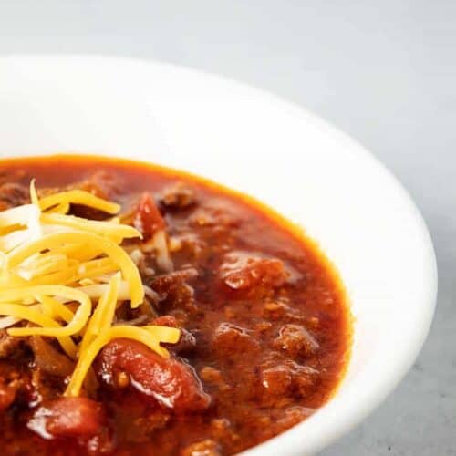 side view of white bowl containing keto chili topped with cheese