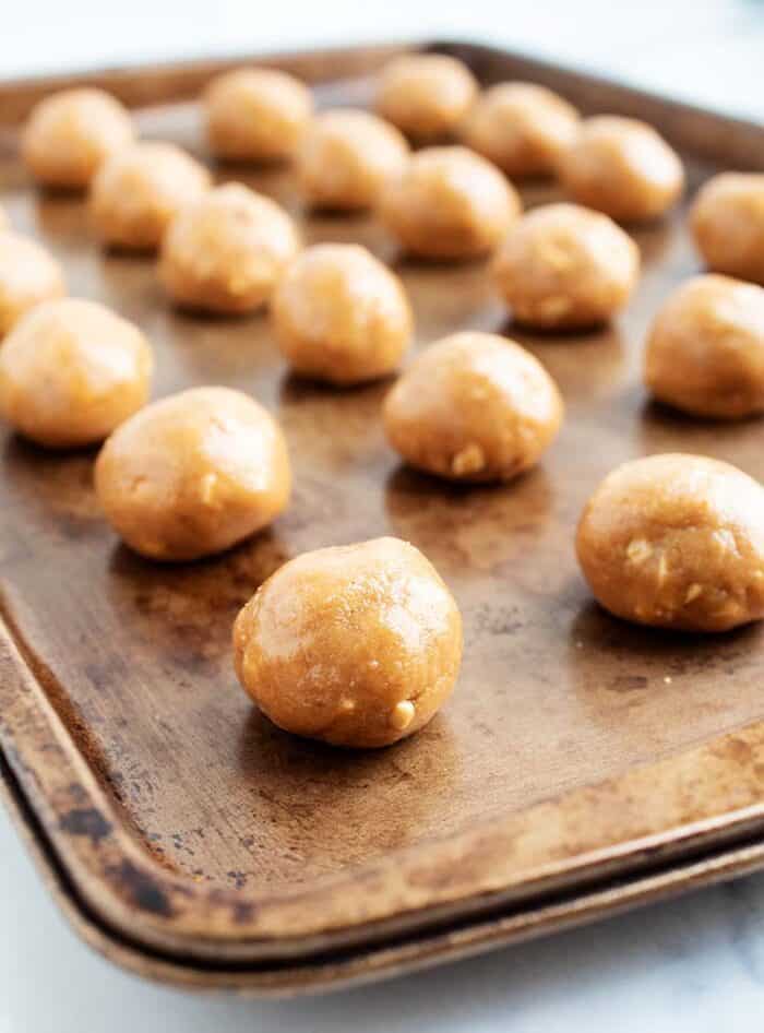 3 ingredient peanut butter balls lined up on a baking tray