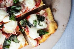overhead view of keto margherita pizza with slice cut out