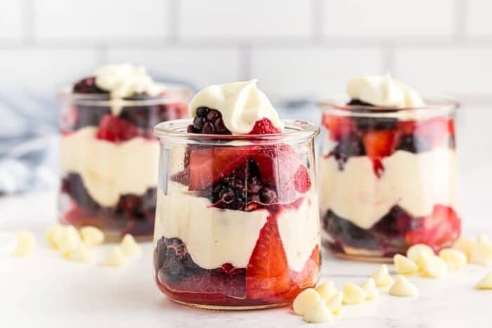 closeup view of three glass jars containing keto white chocolate mousse layered with berries