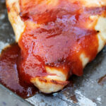 keto bbq chicken smothered with sauce on baking sheet