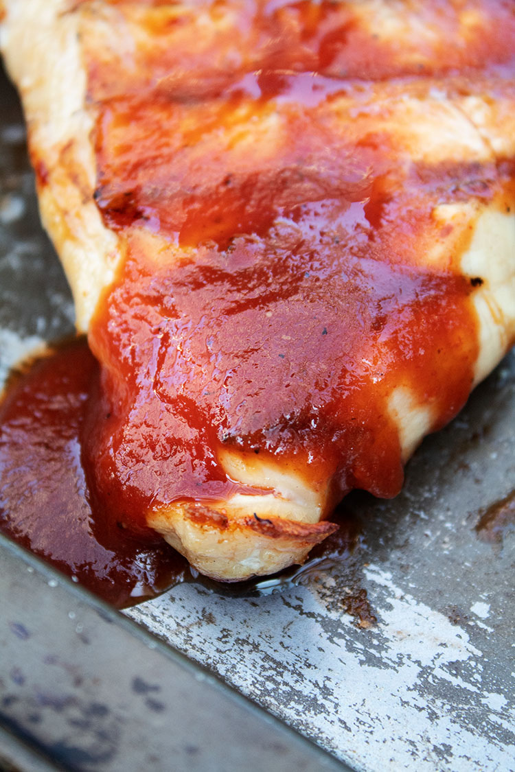 keto bbq chicken smothered with sauce on baking sheet