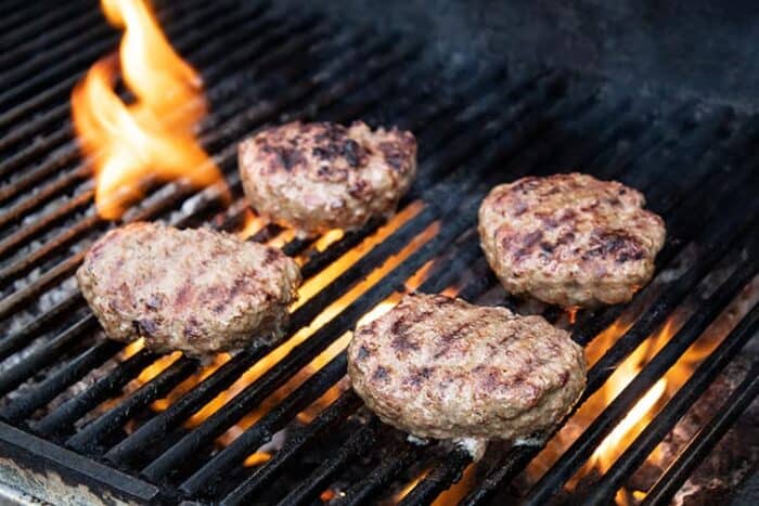 keto burger patties on a grill with a flame