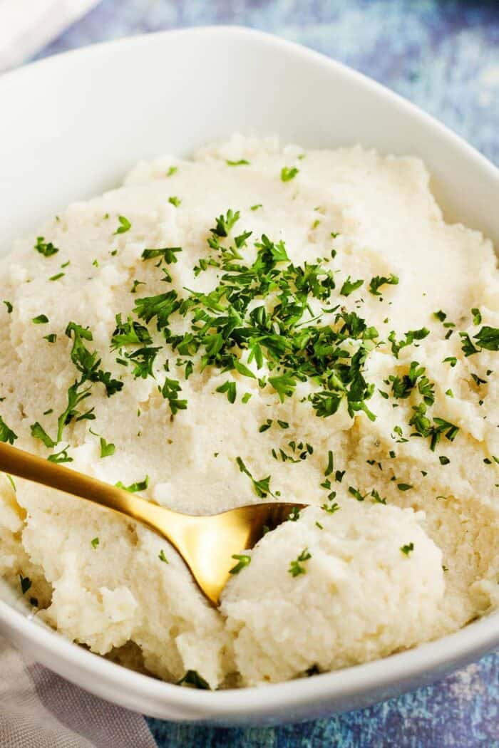 bowl of cauliflower mashed potatoes keto with gold spoon dipping in