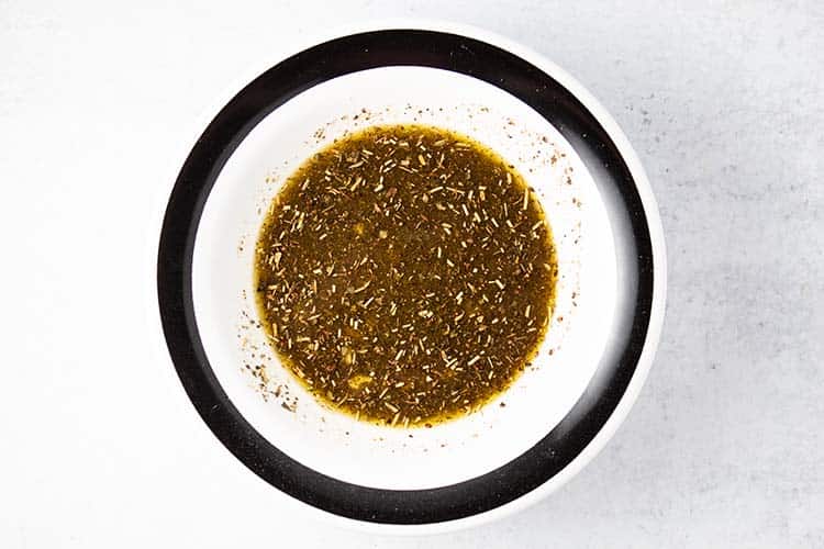oil and vinegar sauce in small bowl with black rim