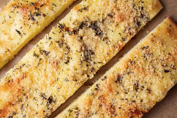 closeup of three pieces of keto garlic bread on parchment paper