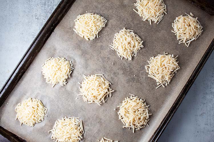 shredded parmesan cheese on a parchment paper-lined baking sheet