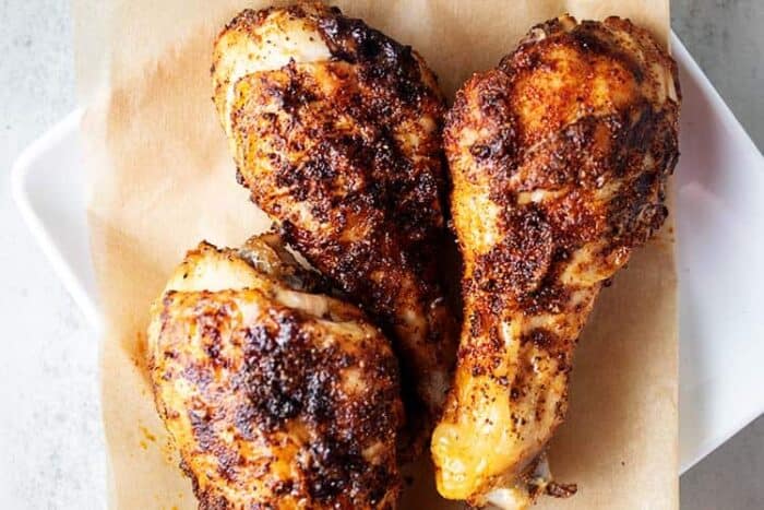 air fryer chicken leg drumsticks on parchment paper on a white plate