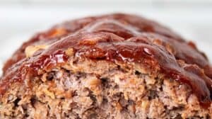 sideview of keto low carb meatloaf with ketchup glaze on a white serving dish