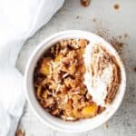 overhead view of white serving bowl filled with sugar free keto keto apple crisp with white cloth next to it