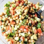 overhead view of chickpea salad with cucumbers and avocado in a glass serving bowl