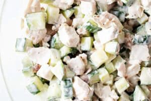 overhead view of chicken cucumber salad in a glass serving bowl ready to be served