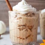 sideview of keto pumpkin fluff in serving glass topped with whipped cream and cinnamon stick straw