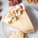 overhead view of a slice of keto no bake pumpkin cheesecake topped with whipped cream and cinnamon on a serving dish
