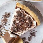 overhead view of keto chocolate pie topped with sugar free whipped cream and chocolate shavings on a swerving dish with a gold fork