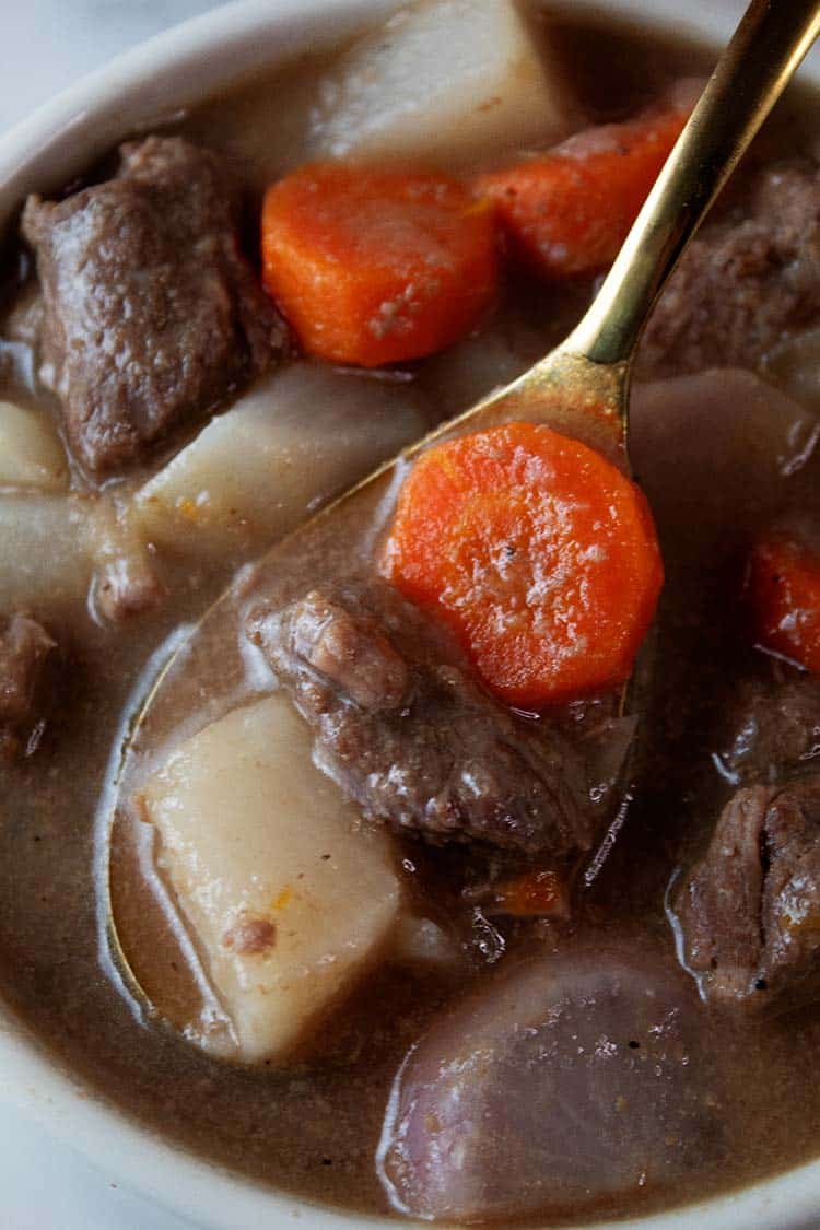 overhead view of keto beef stew ready to serve with a gold serving spoon