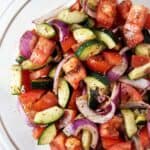 overhead view of cucumber and tomato salad ready to serve in glass serving bowl