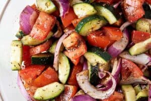 overhead view of cucumber and tomato salad ready to serve in glass serving bowl