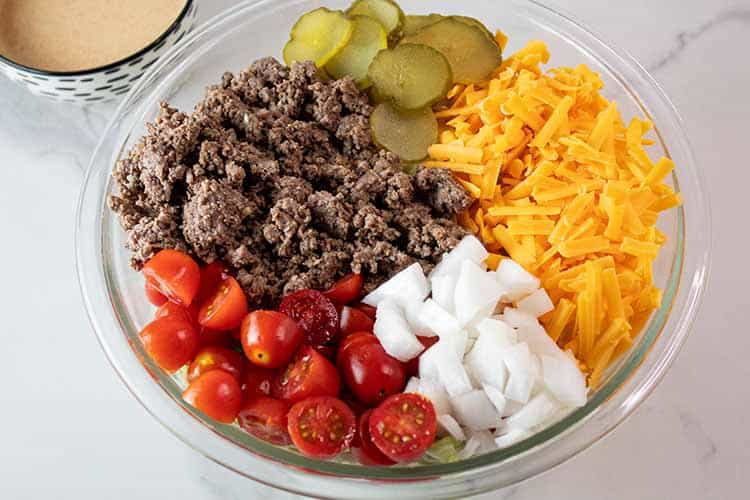 overhead view of salad ingredients spaced separately in a glass mixing bowl
