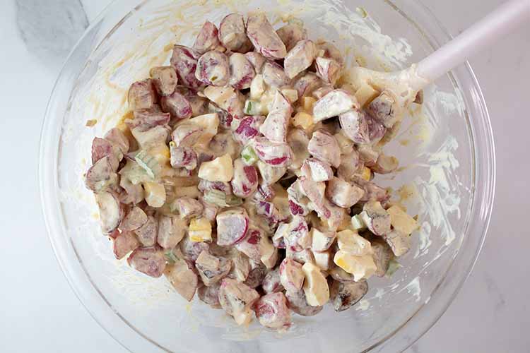 overhead view of low carb potato salad in a glass mixing bowl and spatula