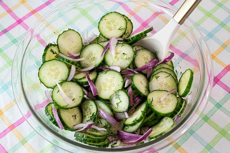 Gurkensalat in einer geworfenen Glasmischung geworfen und bereit, mit einem weißen Servicelöffel zu dienen
