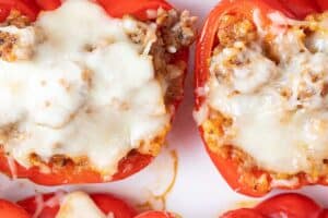 overhead view of six Italian sausage stuffed peppers evenly spaced on a serving dish