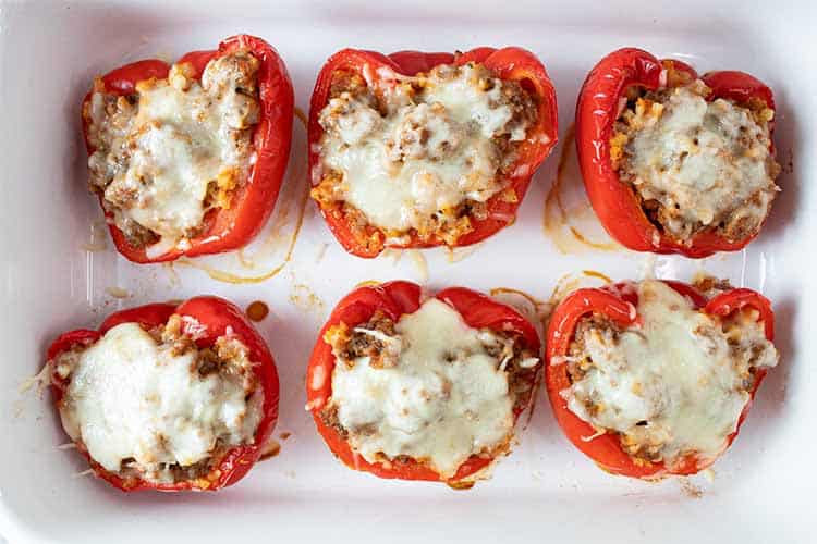 overhead horizontal view of six low carb Italian sausage stuffed peppers evenly spaced on a serving dish
